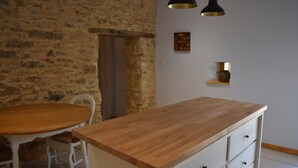 Una cocina rústica con una mesa y sillas de madera, una pared de piedra e iluminación colgante.