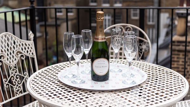 A bottle of champagne on a table surrounded by glasses, set on a balcony with a city view. - Stunning haven for 6 guests in the heart of London (London)