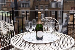 Une table avec une bouteille de champagne et plusieurs verres, le tout posé sur une nappe blanche à motifs floraux.