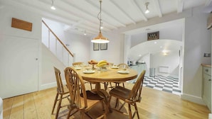 A dining area with a wooden table and chairs, a hanging light fixture, and a staircase leading to another room. - Stunning haven for 6 guests in the heart of London (London)