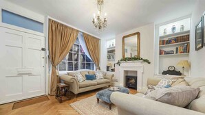 A living room with a fireplace, a bookshelf, and a large mirror. - Stunning haven for 6 guests in the heart of London (London)