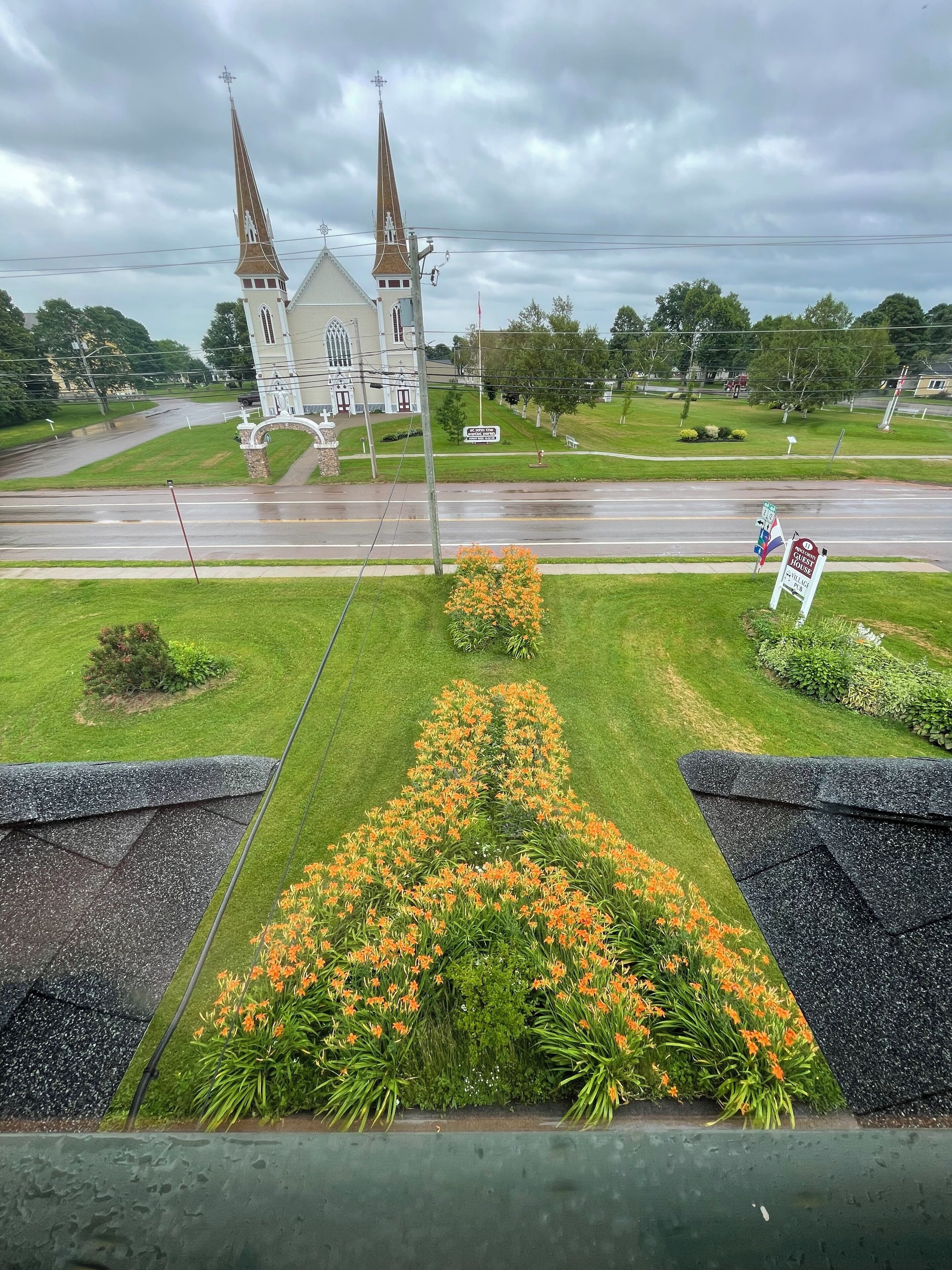 A church with two spires and a signboard in the foreground.