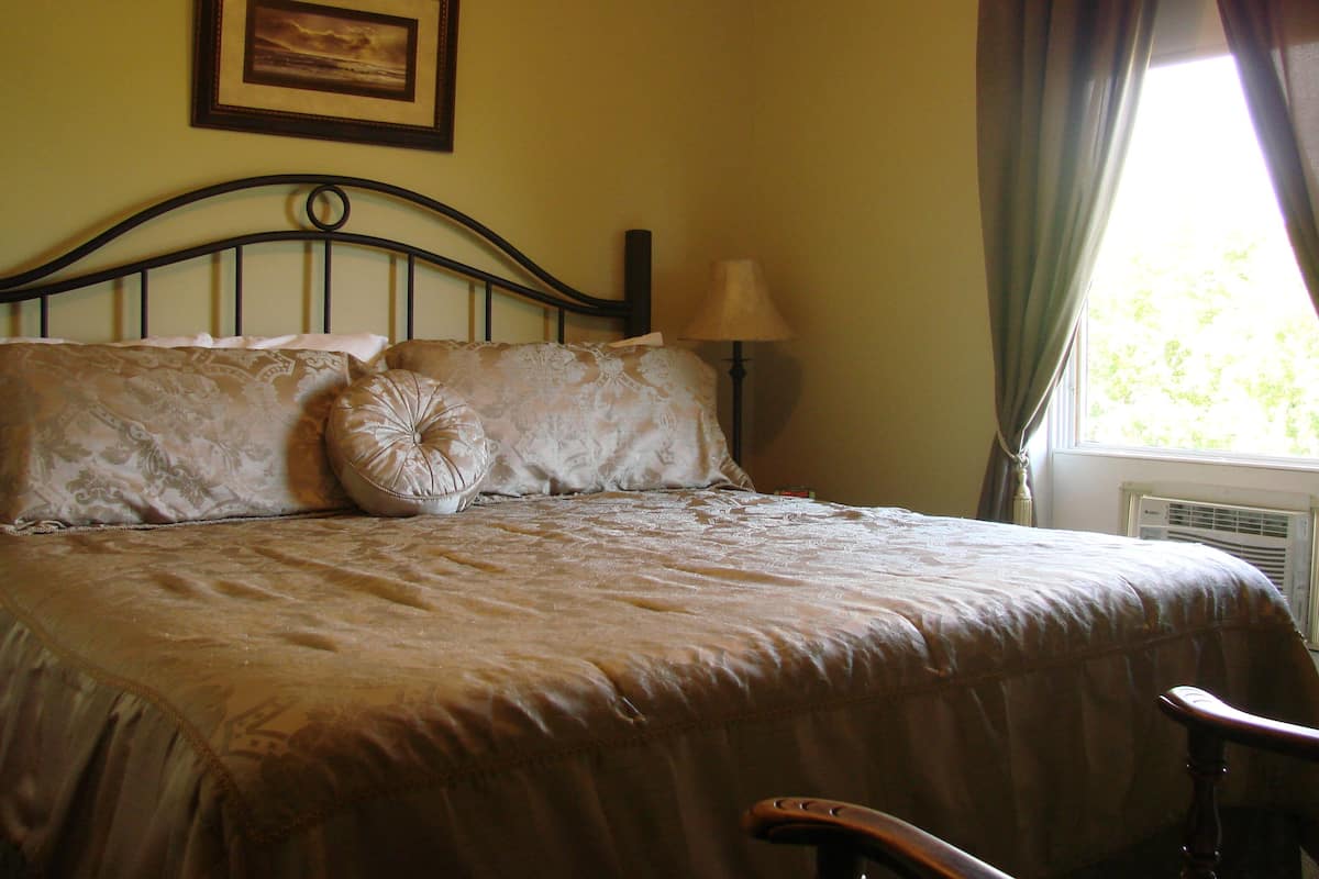 A bed with a headboard, a bedside lamp, and a window with curtains.
