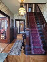 A grand staircase with a patterned carpet leading to a door.