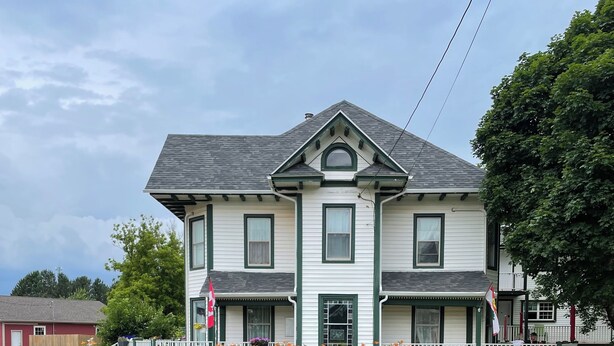 A two-story house with a symmetrical facade, a central entrance, and a small porch with a white picket fence.
