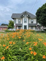 A two-story house with a symmetrical facade, a central entrance, and a small porch with a white picket fence.
