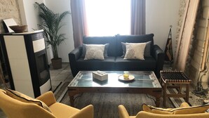 Un salon comprenant un canapé, deux fauteuils jaunes, une table basse et une petite table d’appoint.