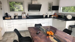 Une cuisine moderne avec des meubles blancs, un plan de travail noir et une table à manger avec des chaises.