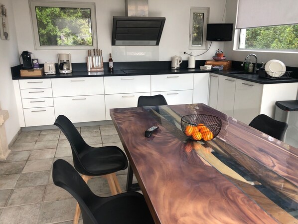 A modern kitchen with white cabinets, a black countertop, and a dining table with chairs.