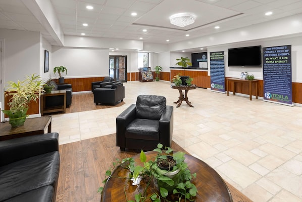 A spacious lobby with leather seating, a reception desk, and informational posters. - Ramada by Wyndham Butler/Tesla Biohealing Resort (Butler)