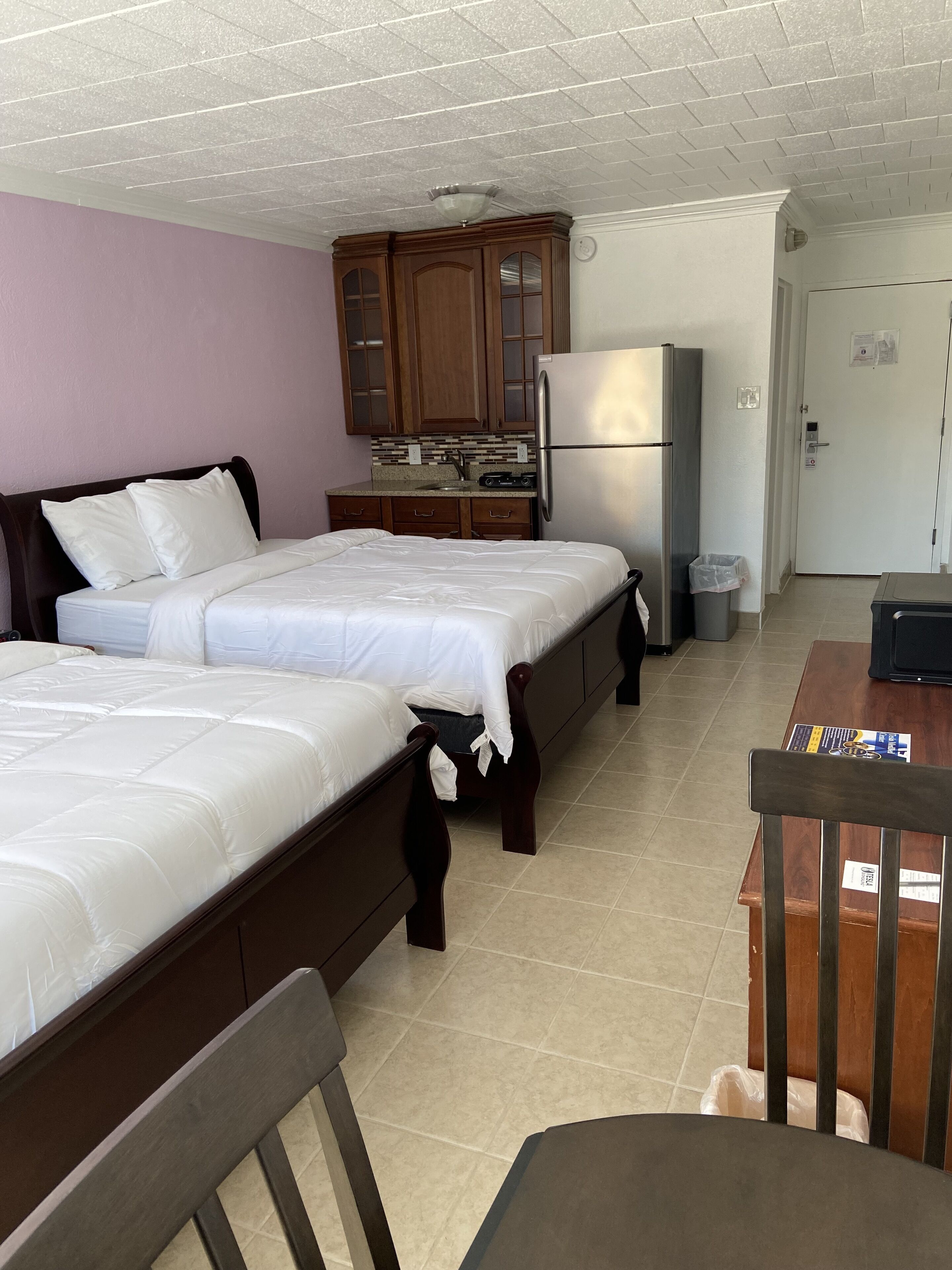 Ein Hotelzimmer mit zwei Betten, einer Küchenzeile und einer Tür.