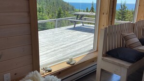 Houten cabinestijl interieur met een groot raam met uitzicht op een terras en de oceaan.