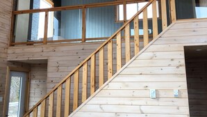 Een houten trap met een leuning die naar een balkon op de tweede verdieping leidt.