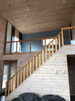 Staircase leads to an upper level, flanked by wooden walls and featuring a handrail.