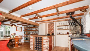 Een keuken met zichtbare houten balken, een keukeneiland van baksteen en houten vloeren.