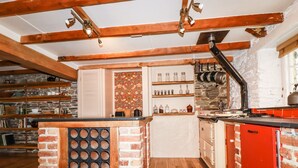 Een rustieke keuken met zichtbare houten balken, een keukeneiland van baksteen en een rode kast.