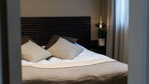 A neatly made bed with a headboard, pillows, and a blanket. - Keflavik Luxury Apartments (Reykjanesbær)