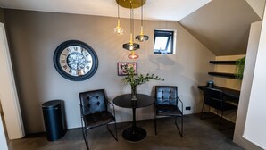 A modern interior with a round table, two chairs, a large wall clock, and a small window. - Keflavik Luxury Apartments (Reykjanesbær)