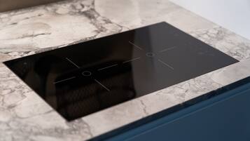 A kitchen with a built-in induction cooktop and a marble countertop.