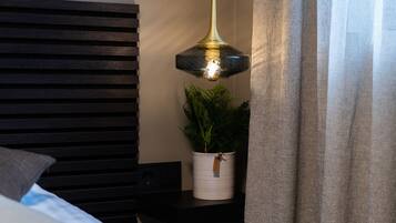 Un dormitorio moderno con un cabecero de listones de madera, una mesita de noche con una planta y una lámpara colgante.