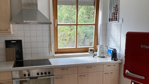 A kitchen with a stove, oven, and a window with blinds. - 3,5 Zimmer Ferienwohnung am Fuße der Schwäbischen Alb Balingen (Balingen)