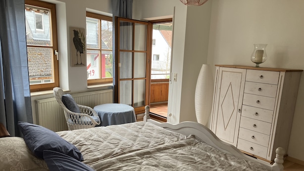 A bedroom with a bed, a dresser, a chair, and a view of the outside. - 3,5 Zimmer Ferienwohnung am Fuße der Schwäbischen Alb Balingen (Balingen)