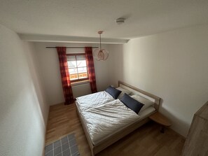 A small, well-lit bedroom with a single bed, a nightstand, a window with curtains, and a ceiling fan. - 3,5 Zimmer Ferienwohnung am Fuße der Schwäbischen Alb Balingen (Balingen)