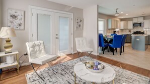 A modern living room with a white sofa, a dining area with blue chairs, and a kitchen with white cabinets. - Close to DC excellent location (Temple Hills)