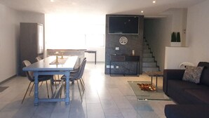 A modern living space with a dining area, a sofa, a staircase, and a kitchen area. - Parco Vira Apartments (Porza)