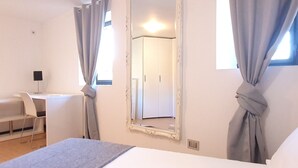 A bedroom with a bed, a desk, a chair, and a mirror. - Parco Vira Apartments (Porza)