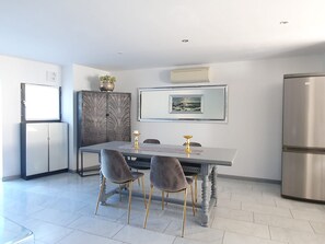A modern kitchen with a dining table, two chairs, a refrigerator, and a decorative cabinet. - Parco Vira Apartments (Porza)