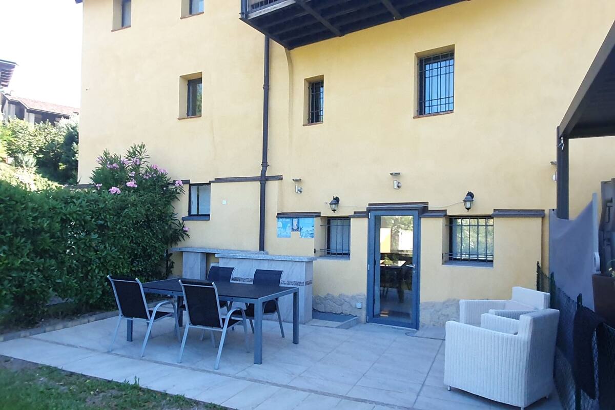 An outdoor patio area with a table and chairs, a white sofa, and a door leading to an interior space.