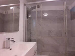 A modern bathroom with a glass shower enclosure, a white sink, and a large mirror. - Parco Vira Apartments (Porza)
