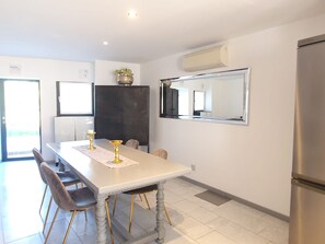 A modern kitchen with a white table, gold chairs, and a large mirror. - Parco Vira Apartments (Porza)