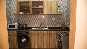 A compact kitchen with a microwave, sink, stove, and washing machine. - Captivating 1-bed Apartment in Tema, com 25 (Tema)