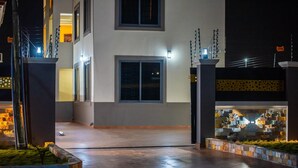 A modern building with a flat roof, large windows, and a paved entrance area. - Captivating 1-bed Apartment in Tema, com 25 (Tema)