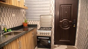 A compact kitchen with a gas stove, sink, and wooden cabinets. - Captivating 1-bed Apartment in Tema, com 25 (Tema)