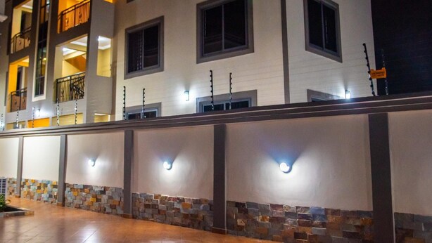 A multi-story hotel with a stone facade and illuminated windows. - Captivating 1-bed Apartment in Tema, com 25 (Tema)