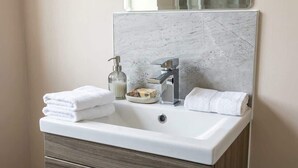 Un baño con un lavabo blanco, un espejo, dispensador de jabón y una toalla.