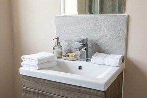 Ein Badezimmer mit Waschbecken, Spiegel, Seifenspender und Handtuch.