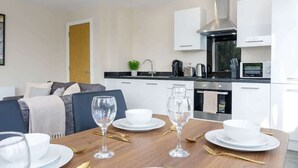 Una cocina moderna con armarios blancos, una campana extractora de acero inoxidable y un horno empotrado.