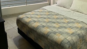 A bedroom with a large window, a bed, and an air conditioning unit.