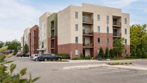 A multi-story residential building with a parking lot in front.