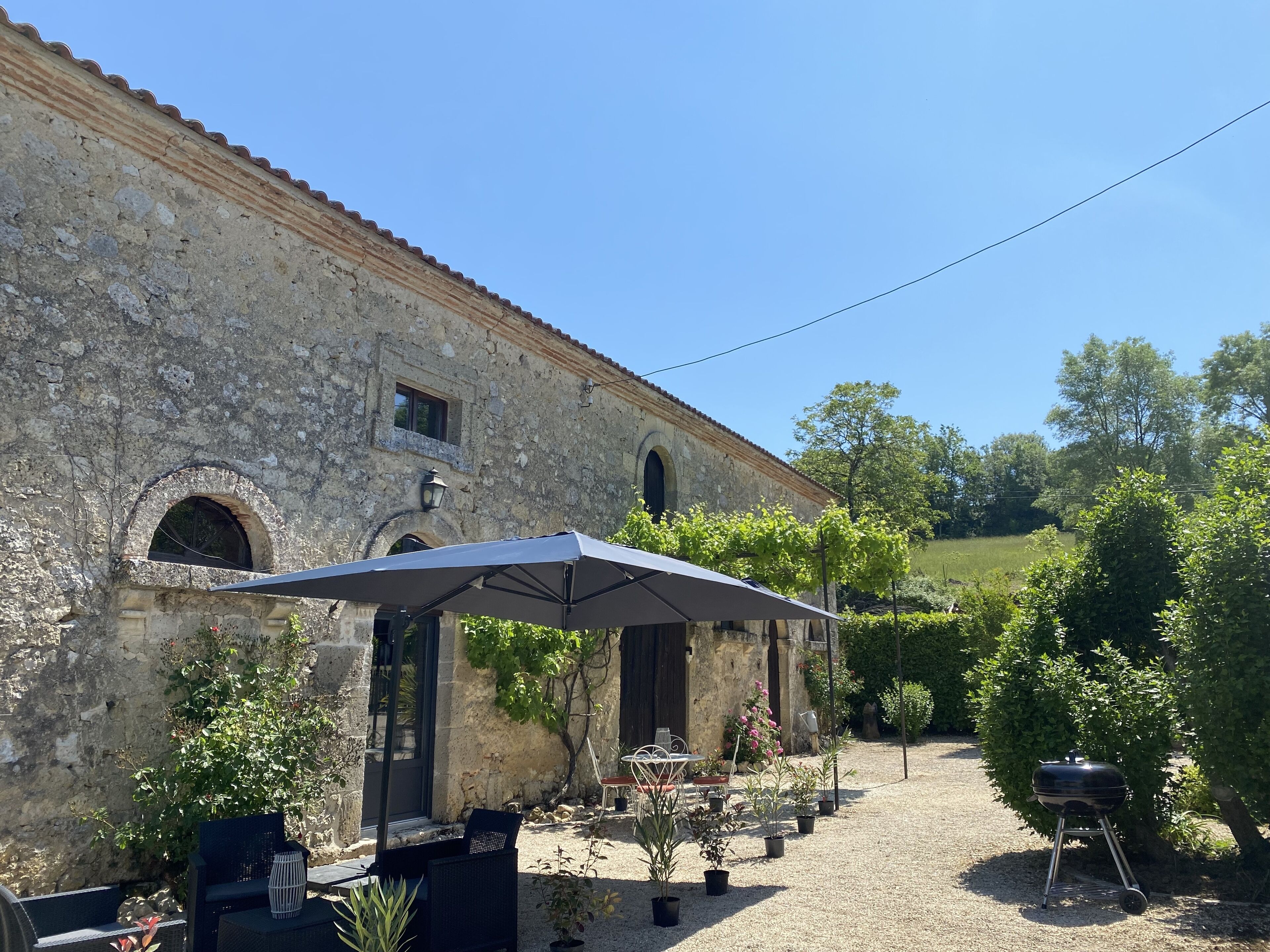 An outdoor patio with stone walls, a pergola, and potted plants.