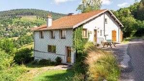 A two-story house with a tiled roof, a wooden door, and a bench outside. - Les Pistes de Ventron (Ventron)