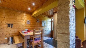 A wooden interior with a dining table, chairs, and a stone pillar. - Les Pistes de Ventron (Ventron)