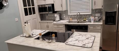 Una cocina moderna con una isla central, electrodomésticos de acero inoxidable y un salpicadero con diseños geométricos.