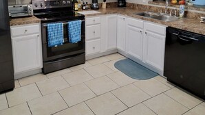 Une cuisine moderne avec des meubles blancs, une cuisinière noire et un lave-vaisselle encastré.