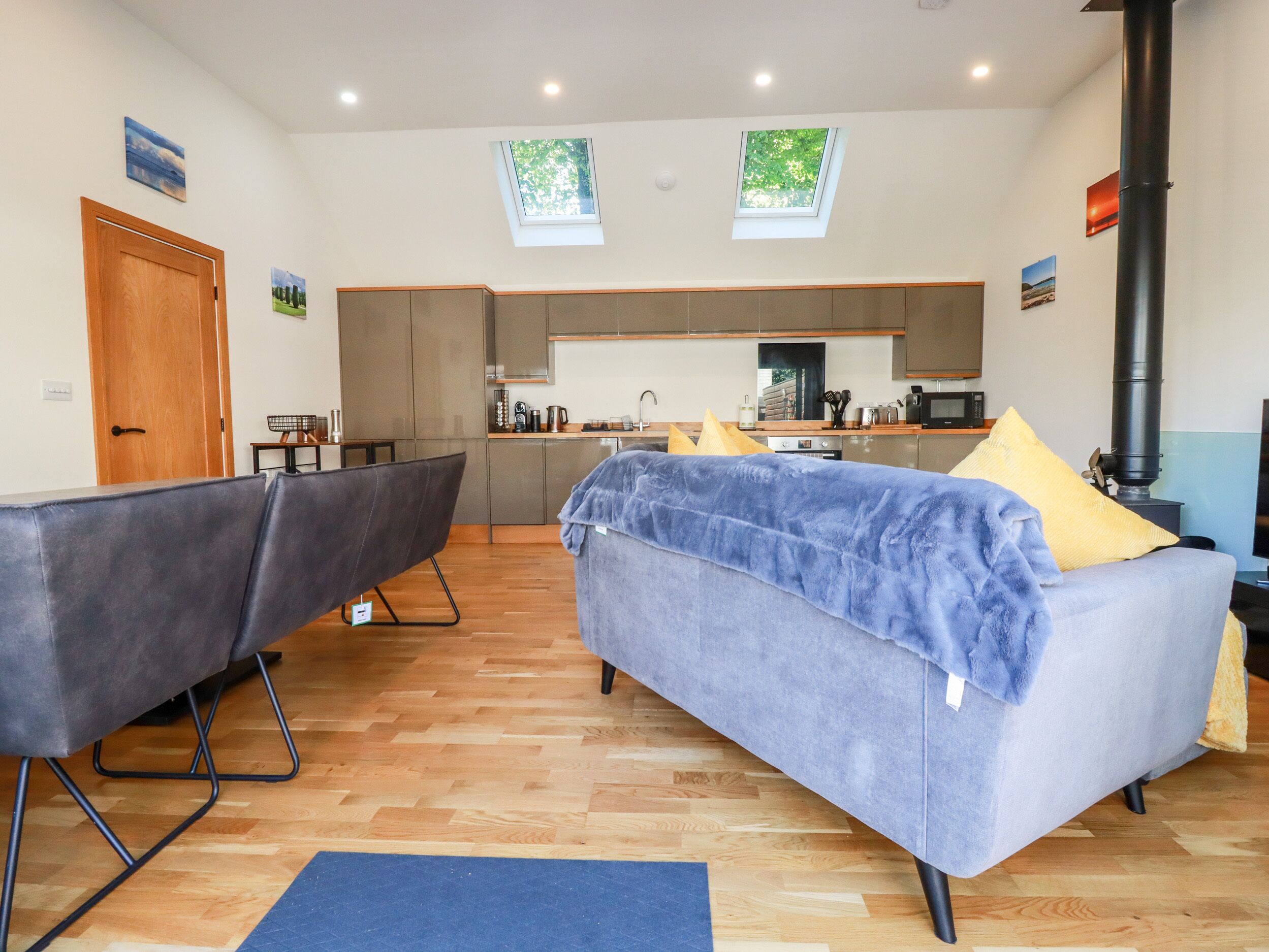 A modern living room with a sofa, a dining area, and a kitchen.