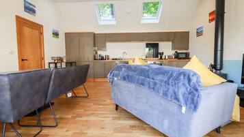 A modern living room with a sofa, a dining area, and a kitchen.